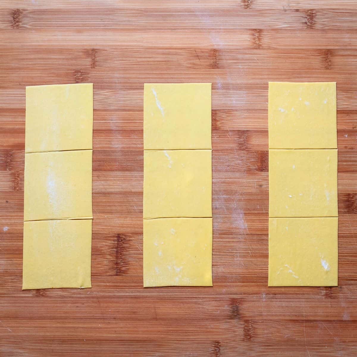 Large pasta squares on a wooden board.