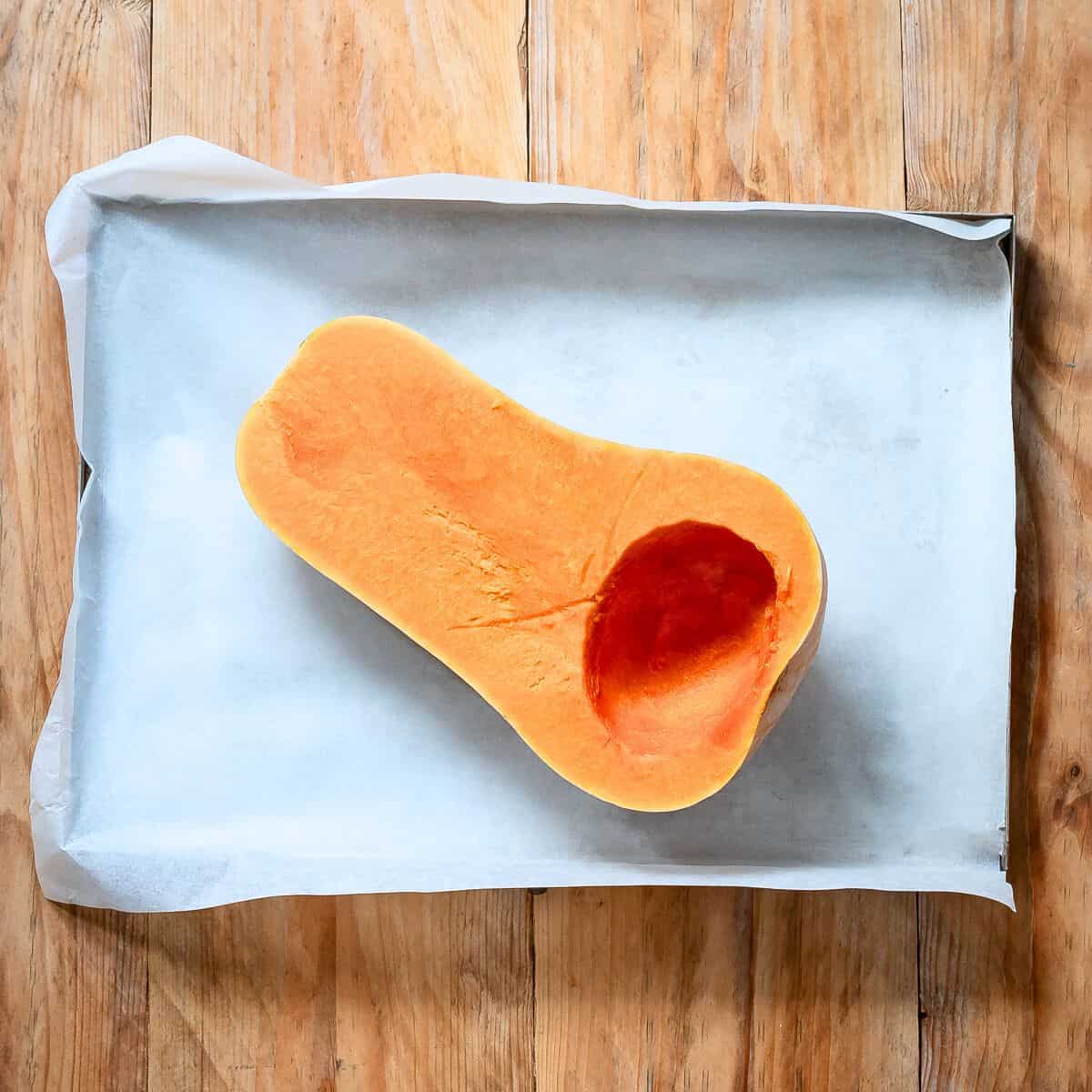 Butternut squash half of a baking tray.